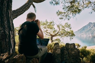Man sitting in nature with a laptop